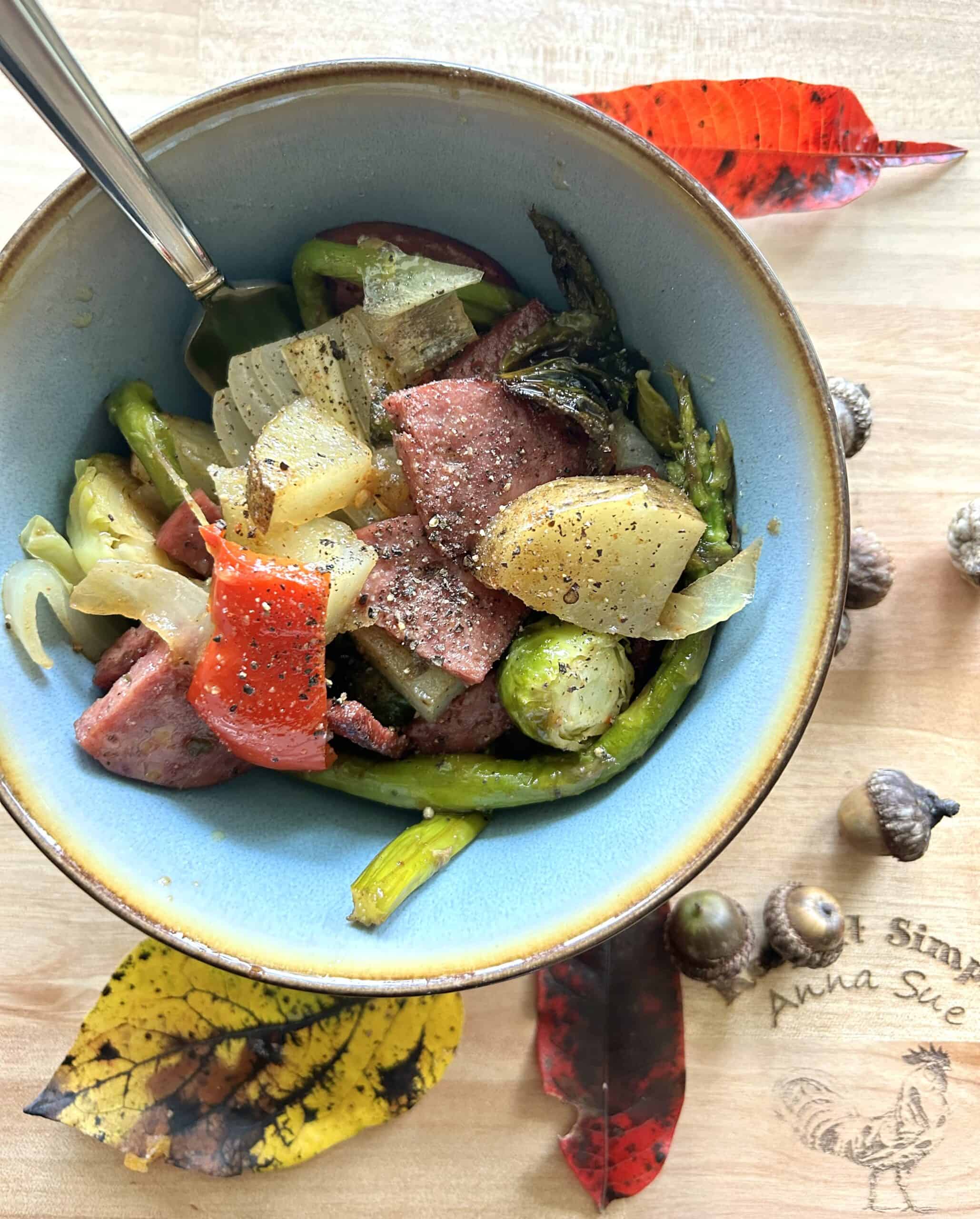 roasted-veggies-with-skillet-fried-deer-salami-in-a-blue-bowl-surrounded-by-natural-elements-like-leaves-and-acorns-