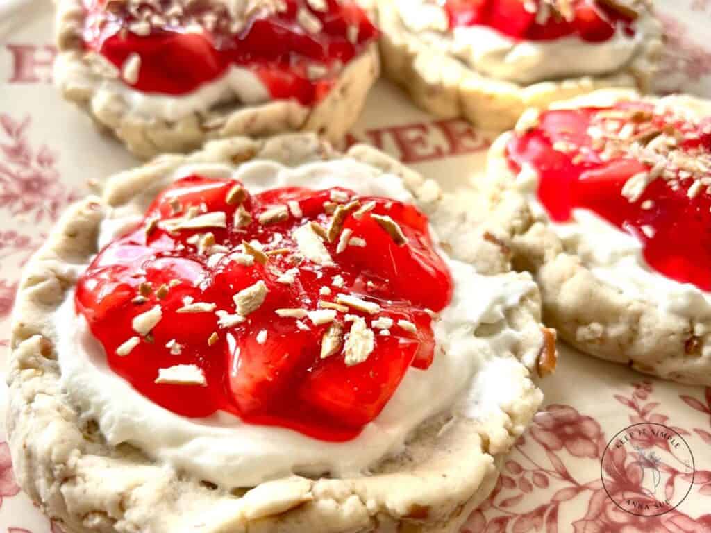 strawberry-pretzel-pie-cookies-with-a-cream-cheese-filling-and-topped-with-a-strawberry-glaze-on-a-beautiful-red-plate-topped-with-pretzel-pieces-up-close-image-of-one.jpg