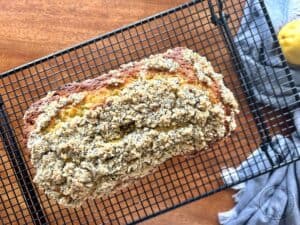 baked-lemon-poppy-seed-streusel-bread-on-a-wire-cooling-rack-with-a-blue-towel-and-fresh-lemons-1.jpg