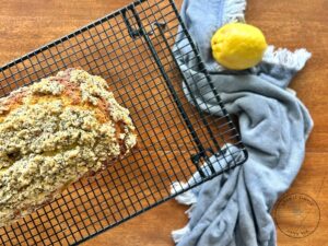 baked-lemon-poppy-seed-streusel-bread-on-a-wire-cooling-rack-with-a-blue-towel-and-fresh-lemons.jpg