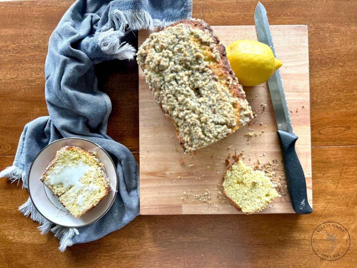 baked-lemon-poppy-seed-streusel-bread-on-a-wire-cooling-rack-with-a-blue-towel-and-fresh-lemons-and-a-sliced-plated-on-a-beautiful-china-1.jpg
