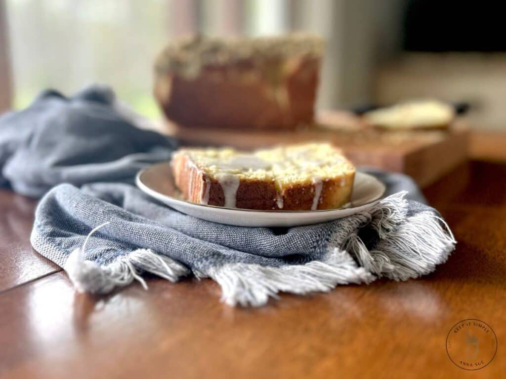 baked-lemon-poppy-seed-streusel-bread-on-a-wire-cooling-rack-with-a-blue-towel-and-fresh-lemons-and-a-sliced-plated-on-a-beautiful-china.jpg