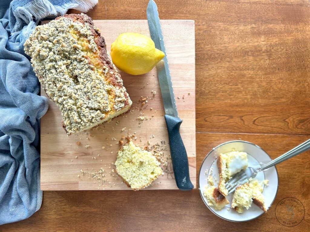 baked-lemon-poppy-seed-streusel-bread-on-a-wire-cooling-rack-with-a-blue-towel-and-fresh-lemons-and-a-sliced-plated-on-a-beautiful-china-and-a-fork-and-crumbs.jpg